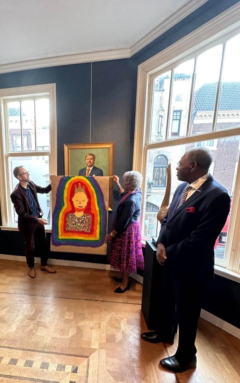 De Gouverneur van Curacao en de maker van het nieuwe Staatsieportret onthullen deze door het doek van het schilderij af te tillen.