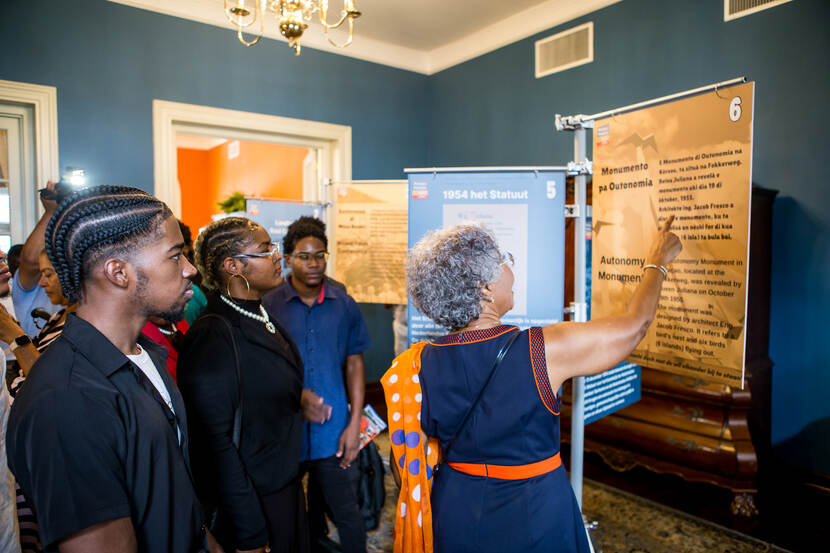 Op deze foto kijkt de Gouverneur van Curaçao samen met bezoekers naar informatie van het Mongui Maduro Museum in de blauwe kamer van het Gouverneurshuis.