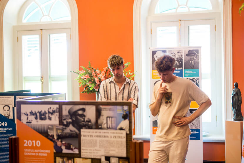 Jongeren die de informatie van de Electorale Raad lezen, in de oranje kamer van het Gouverneurshuis.