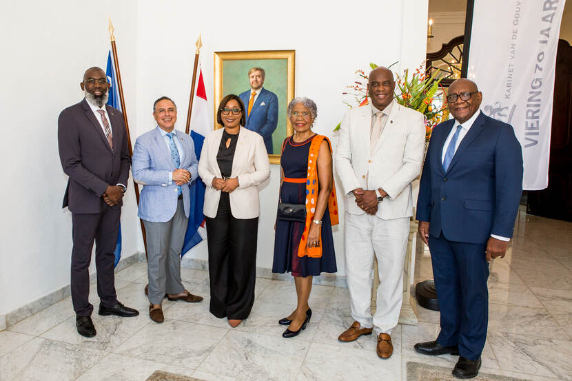 De Gouverneur van Curaçao staat op deze foto bij het nieuwe portret van Koning Willem-Alexander. Naast haar staan de deelnemers van het rondetafelgesprek op 15 december jl.